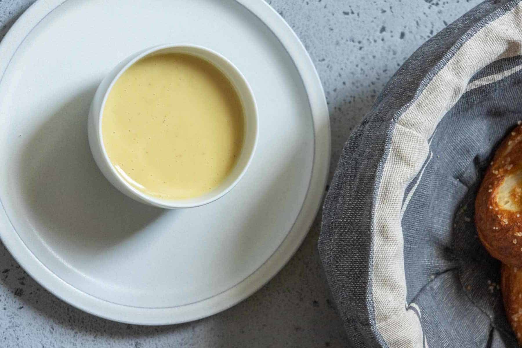 Overhead of small white bowl containing honey mustard sauce on top of a gray plate.