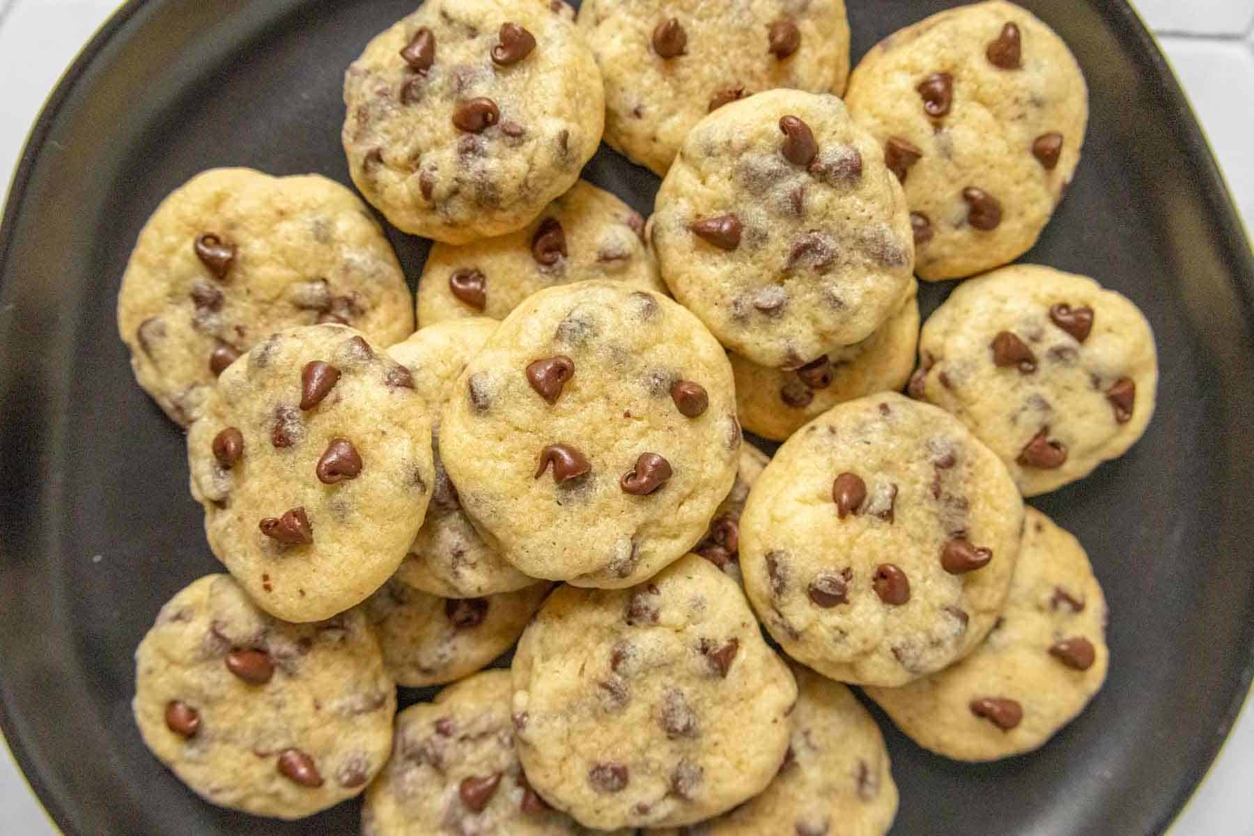 Black plate filled with mini chocolate chip cookies.