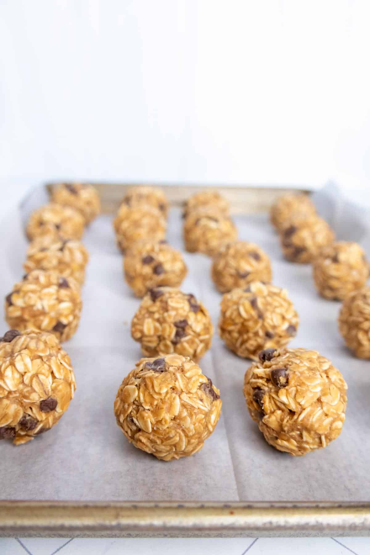 Oatmeal chocolate chip balls arranged on a baking sheet lined with parchment paper.