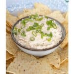 Bowl of dip topped with chopped green onions, surrounded by tortilla chips. Text reads "Taco Dip.