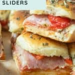 Close-up of stacked Italian sliders made with deli meat, cheese, and roasted red peppers between slices of seasoned bread.