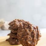 A stack of chocolate oatmeal no-bake cookies on a wooden surface with a light, blurred background.