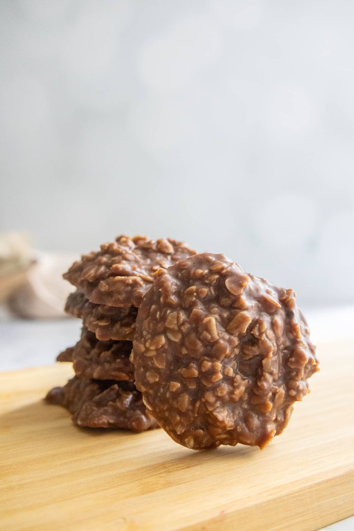 A stack of chocolate oatmeal no-bake cookies on a wooden surface with a light, blurred background.