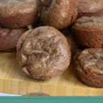 A pile of small, round brownie bites is displayed on a wooden surface with a label at the bottom that reads "BROWNIE BITES" and "happysnackcidents.com".