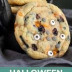 A close-up of Halloween-themed cookies with candy eyes, orange and black chips on a dark cloth, with "HALLOWEEN COOKIES" and a website URL at the bottom.