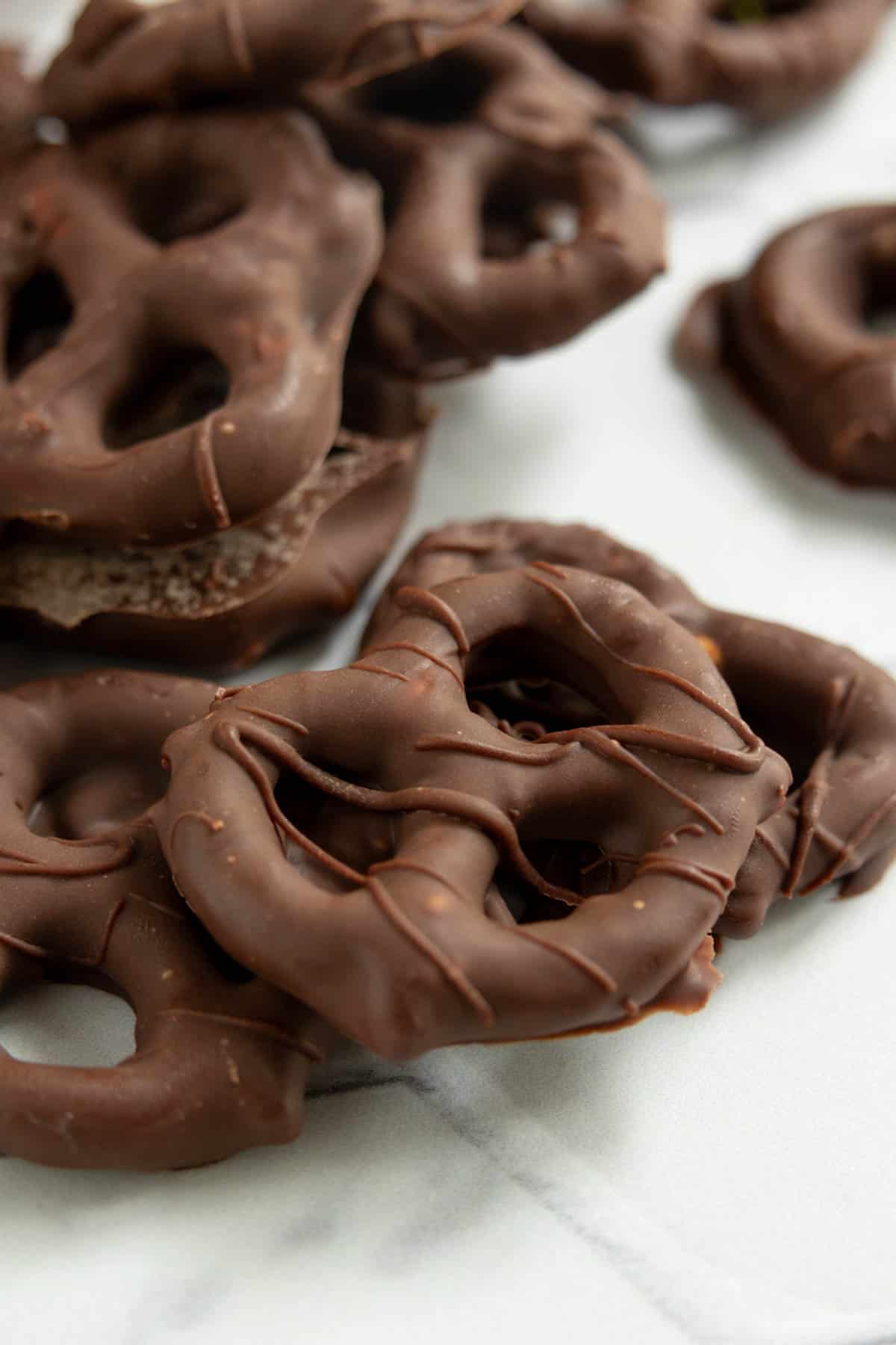 A close-up of several chocolate-covered pretzels on a white surface.