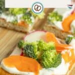 A slice of crescent roll veggie pizza topped with broccoli, carrot slices, radish, and a creamy spread on a wooden surface.