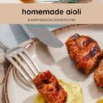 Two grilled meat pieces and a lemon wedge are served on a plate with a dollop of yellow homemade aioli.